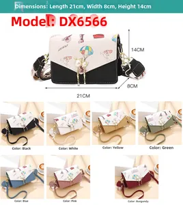 Détail du sac bandoulière carré avec pendentif chat en perle et motifs de voyage