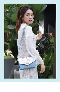 Detail of blue and white handbag with hot air balloon print and gold cat pearl lock