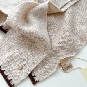 Détail d'un châle en 100% laine pure avec bord brodé et boucle dorée en forme de D