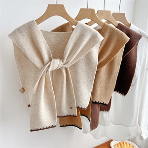 Ensemble de trois châles en laine tricotée crème et marron sur un cintre en bois