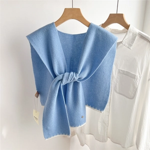 Gros plan d'un châle en tricot bleu clair avec surpiqûres blanches sur cintre