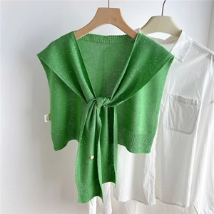 Dettaglio dello scialle in maglia verde erba con paillettes argentate e bordi a coste