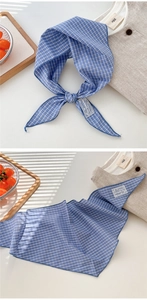 Detail of blue checkered cotton scarf with decorative fabric patch and linen texture