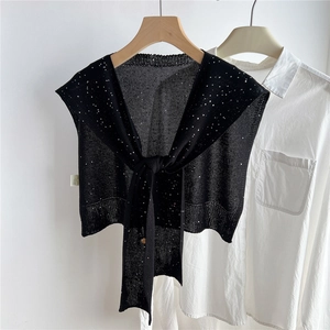 Dettaglio di scialle in maglia nera con paillettes argento e lacci anteriori