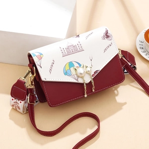 Sac bandoulière bicolore rouge et blanc avec motifs de voyage et boucle chat perle