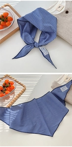 Detailed view of blue plaid cotton scarf showing knot style and texture in natural light