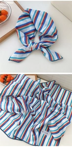 Dettaglio di un foulard a righe colorate in lino e cotone con bordi cuciti di alta qualità