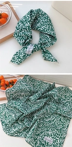 Dettaglio della sciarpa in cotone e lino con motivo astratto verde e bianco e bordo in pizzo