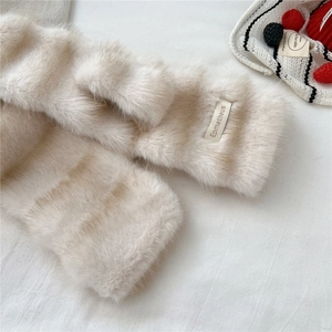 Detail shot of soft cream faux fur scarf showing plush texture and brand label