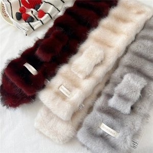 Close-up of soft plush striped scarves in burgundy, cream, and grey with brand labels