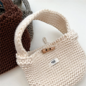 Detail of knitted tote bag showing thick texture and wooden toggle closure button
