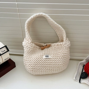 Detail of white knitted tote bag with textured knit pattern and wooden horn button