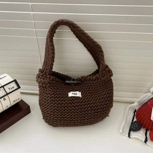 Close-up of brown knitted tote bag featuring a textured pattern and white egg label