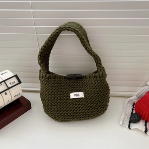 Detail of green knitted tote bag featuring a wooden olive button and minimalist logo tag