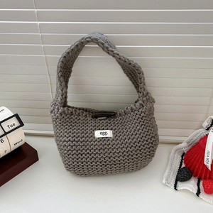 Close-up of grey knitted tote bag with textured crochet pattern and egg. label detail
