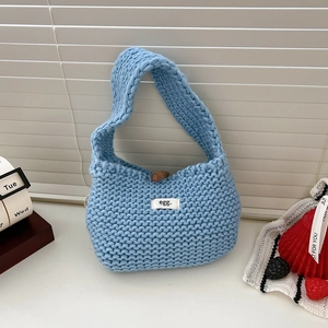 Detail of light blue knit handbag featuring a wood toggle button and soft texture