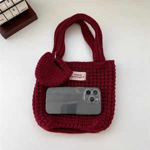 Détail du sac cabas en tricot bordeaux avec étiquette artisanale et pendentif coeur