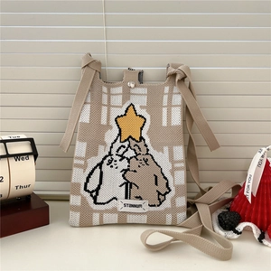 Close-up of checkerboard knitted phone bag with penguin design and magnetic closure