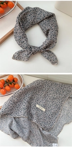 Detail of floral cotton linen neck scarf with woven label and folded texture on tray