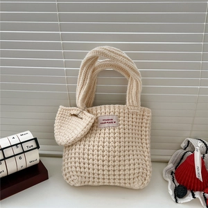 Détail d'un sac cabas en tricot crème avec étiquette faite main et pendentif cœur