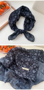 Close-up of black cotton-linen scarf fabric with white floral print and woven tag