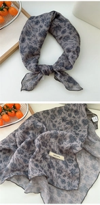Close-up of grey floral cotton linen scarf featuring delicate black flower patterns
