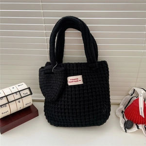 Gros plan du sac cabas noir tricoté à la main avec un charme de cœur et étiquette en tissu