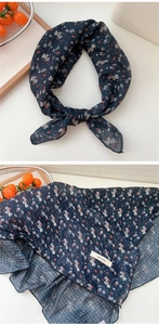 Detail of navy blue cotton linen scarf with orange floral pattern and explore infinity tag