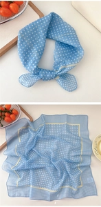 Detail view of light blue polka dot scarf styled in a bow and laid flat on a tray