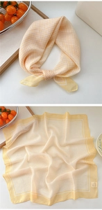 Detail of yellow checkered cotton linen scarf showing soft texture and fine hemmed edges