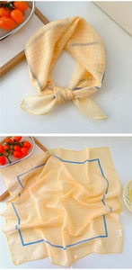 Detail showing bright yellow polka dot scarf with navy blue edges on a white tabletop