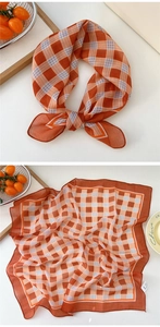 Detailed view of an orange and white checkered cotton linen scarf with smooth stitching