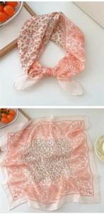 Detail of light pink cotton linen scarf featuring orange paisley prints and hemmed edges