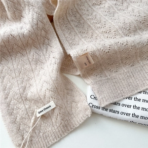 Detail of pointelle knit texture and brand tag on 100% wool cream shawl scarf