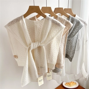 Knitted wool shawls in multiple colors hanging on hangers over white shirts