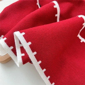 Macro shot of red knitted shawl featuring white wave-patterned jacquard knit edge
