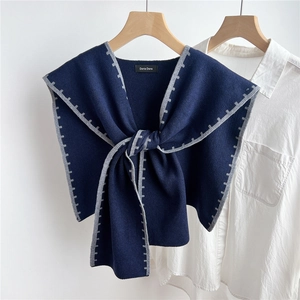 Detail of navy knit shawl with grey stitching and knot design on white shirt