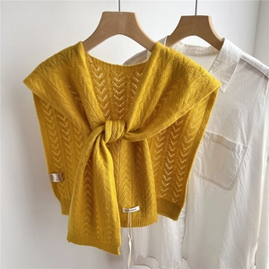 Close-up of ginger yellow 100% wool knit shawl with hollow geometric patterns and a front knot