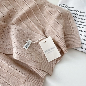 Detailed macro view of beige hollow wave knit pattern and handmade logo label