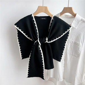 Detail of black knit shawl with white contrast stitching and Doria Dore brand tag