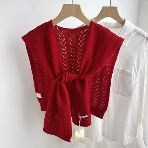 Detail of red hollow-out wool knit shawl layered over a white shirt with elegant knot