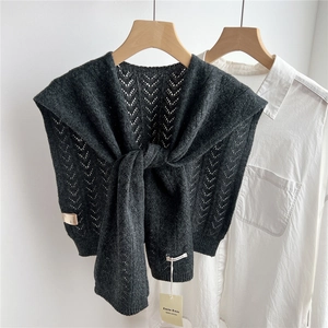 Close-up of a dark grey wool knitted shawl featuring hollow wave texture on a white shirt