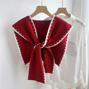 Close-up of wine red knitted shawl with contrast white stitching tied on a white shirt