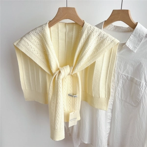 Detail of cream hollow knit shawl with intricate texture draped on a shirt