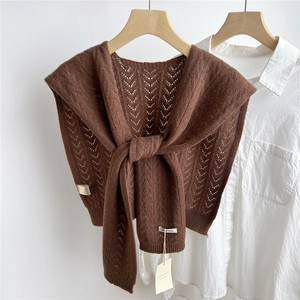 Close-up of brown knit wool shawl with V-shaped cutout patterns and knotted front detail