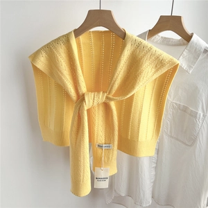 Detail of yellow knitted shawl with vertical stripe texture and tie-knot over white shirt