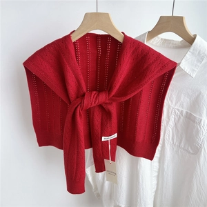 Detail of red hollow-knit shawl with long ties shown on a classic white shirt