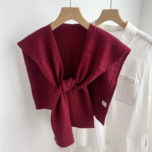 Dettaglio di scialle in maglia bordeaux con trama a nido d'ape su camicia bianca