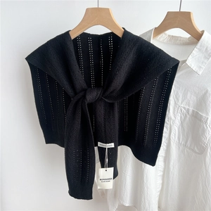 Detail of black hollow knit shawl with vertical stripes over a white shirt