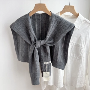 Detail of grey knitted shawl scarf featuring hollow vertical stripes and front tie design